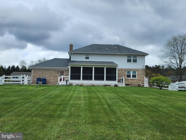 back of house with fence, a lawn, and a sunroom