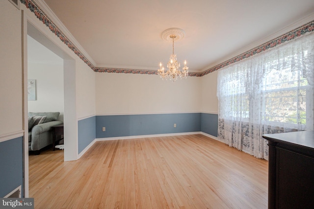 spare room featuring light wood finished floors, baseboards, a chandelier, and ornamental molding