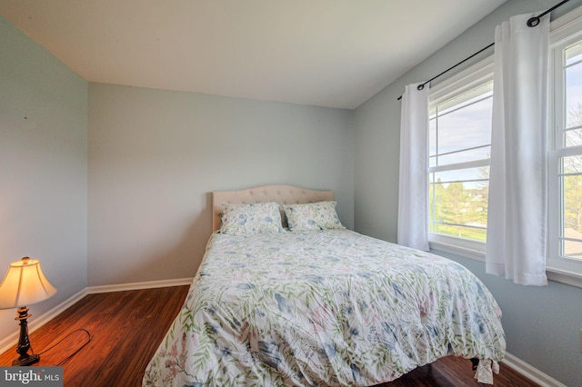 bedroom featuring multiple windows, baseboards, and dark wood-style flooring