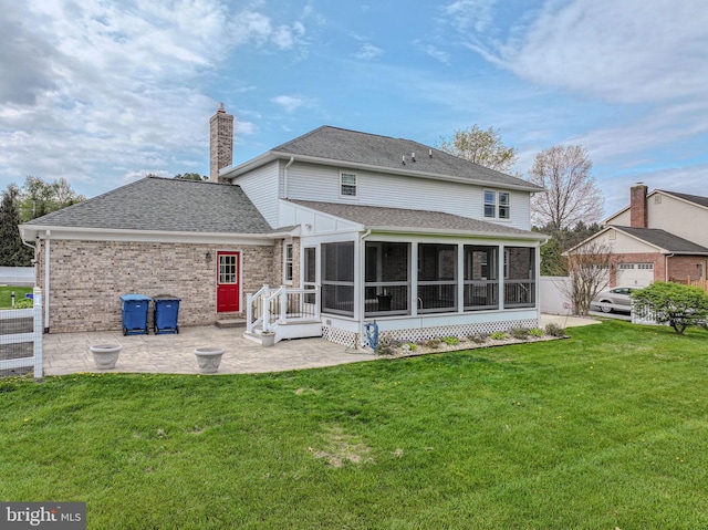back of property featuring a chimney, a shingled roof, a patio, a lawn, and a sunroom