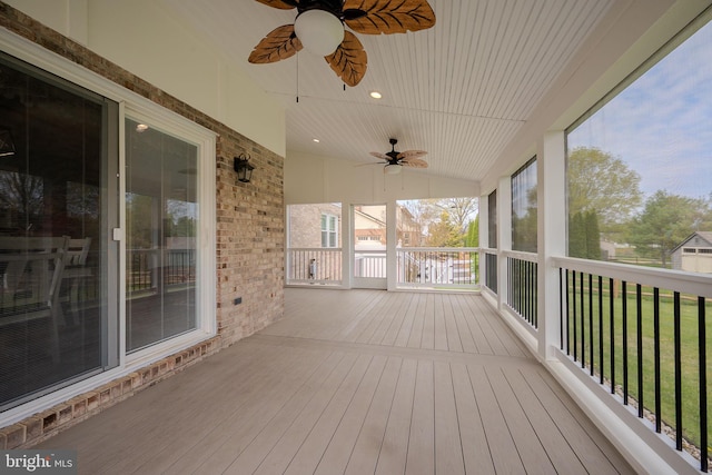 wooden terrace featuring a ceiling fan and a lawn