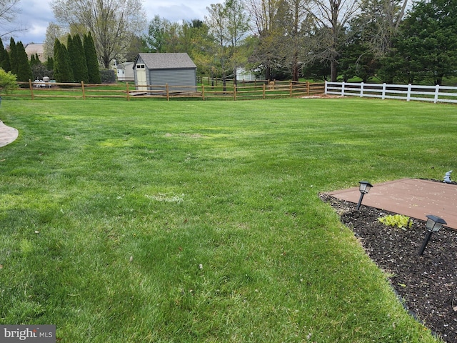 view of yard with fence, an outdoor structure, and a storage shed