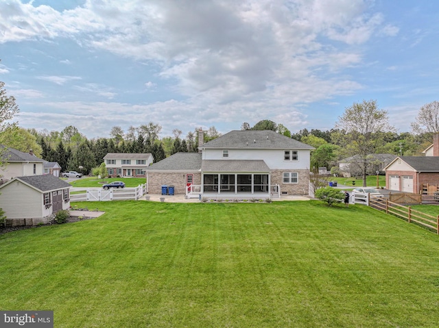 rear view of house featuring a fenced backyard, a gate, a sunroom, and a yard