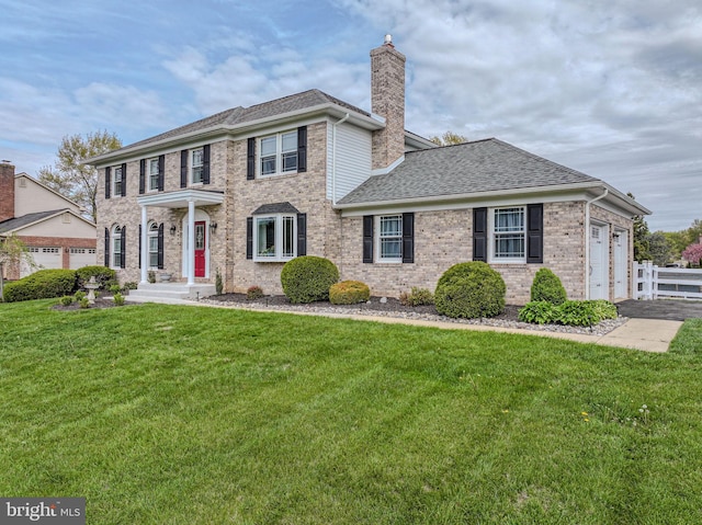 view of front of home with a chimney, a front lawn, brick siding, and fence