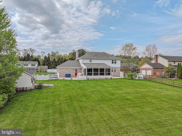 rear view of house with a fenced backyard, a chimney, a yard, a sunroom, and a patio