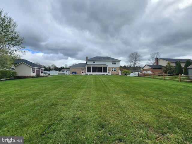 back of property with a lawn and fence