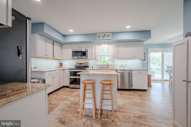 kitchen featuring backsplash, white cabinetry, light stone countertops, and stainless steel appliances
