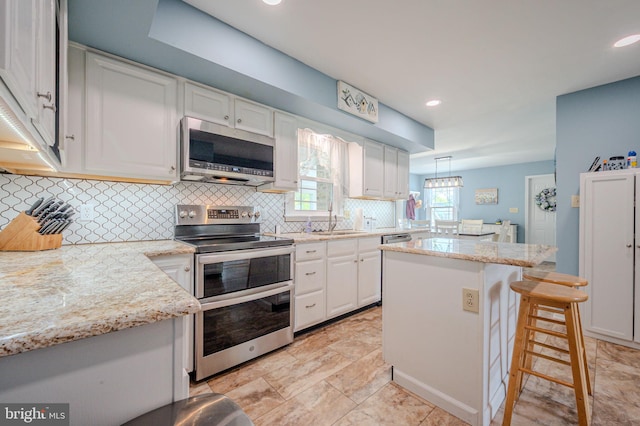 kitchen featuring white cabinets, recessed lighting, stainless steel appliances, a kitchen island, and decorative backsplash