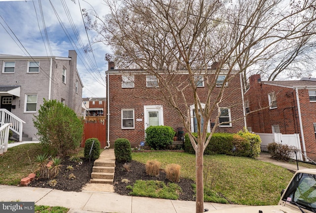 view of front of home with brick siding, fence, and a front lawn