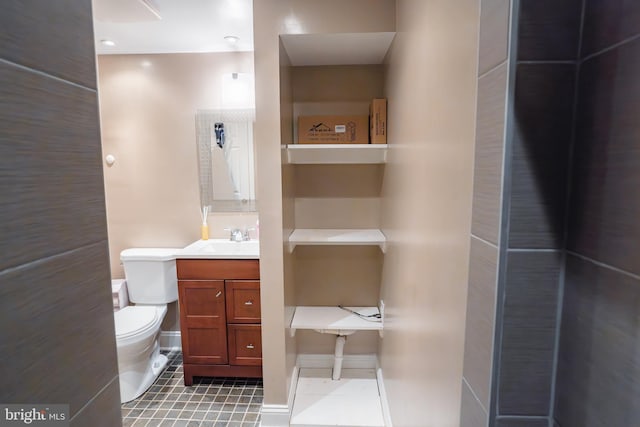 bathroom with toilet, tile patterned floors, vanity, and baseboards