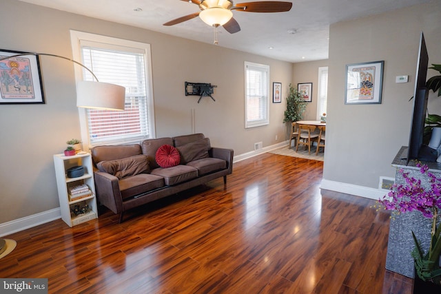 living area with visible vents, baseboards, a ceiling fan, and wood finished floors