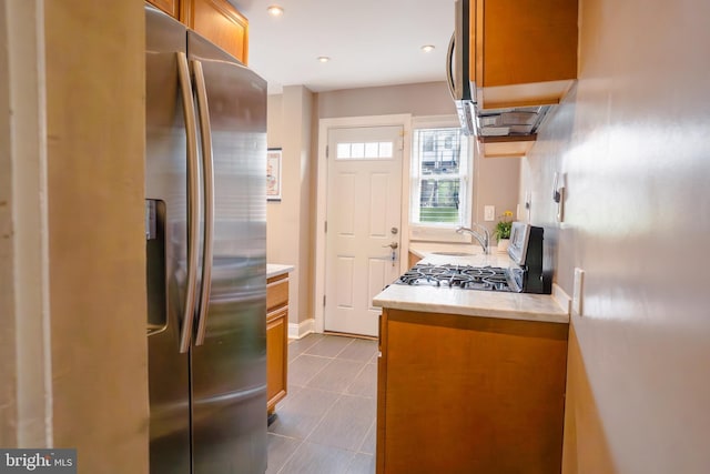 kitchen featuring brown cabinets, light countertops, stainless steel fridge, and baseboards