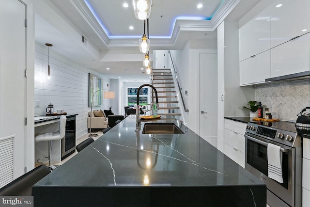 kitchen with dark countertops, stainless steel electric range oven, a sink, and modern cabinets