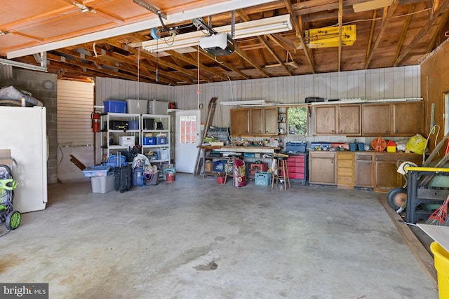 garage with a garage door opener and freestanding refrigerator