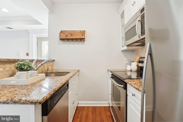 kitchen featuring stainless steel appliances, backsplash, wood finished floors, and a sink