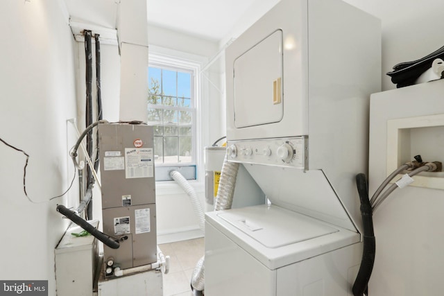 clothes washing area with stacked washer and clothes dryer, light tile patterned flooring, and laundry area