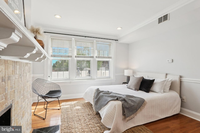 bedroom featuring baseboards, ornamental molding, wood finished floors, and multiple windows