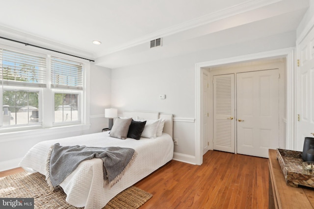 bedroom featuring ornamental molding, visible vents, and wood finished floors