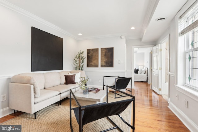 living area with ornamental molding, recessed lighting, visible vents, and light wood-style floors