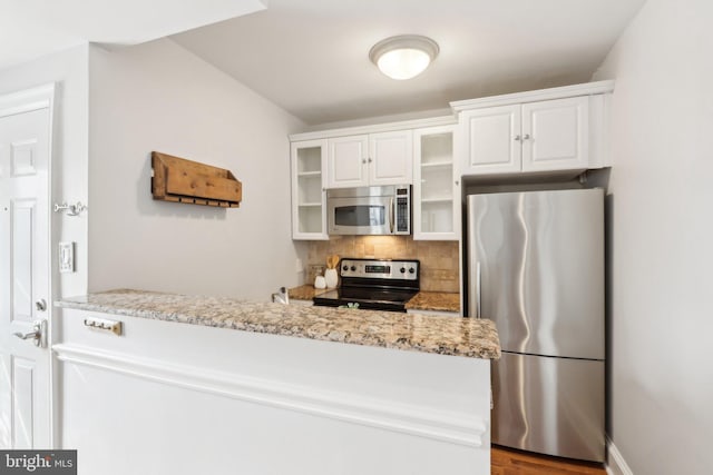kitchen with stainless steel appliances, glass insert cabinets, light stone counters, backsplash, and white cabinets