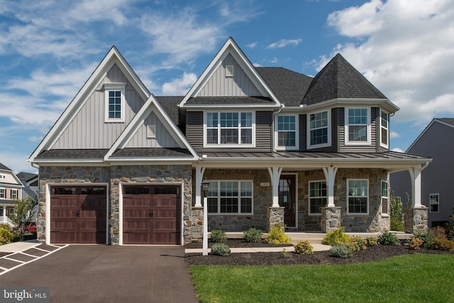 view of front of property with driveway, board and batten siding, stone siding, a standing seam roof, and covered porch