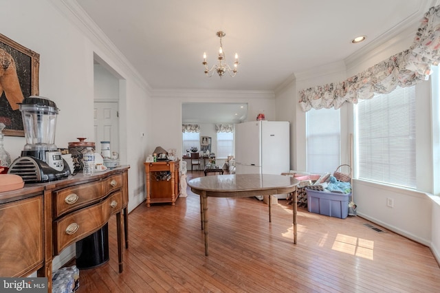 dining room with visible vents, light wood finished floors, crown molding, and an inviting chandelier