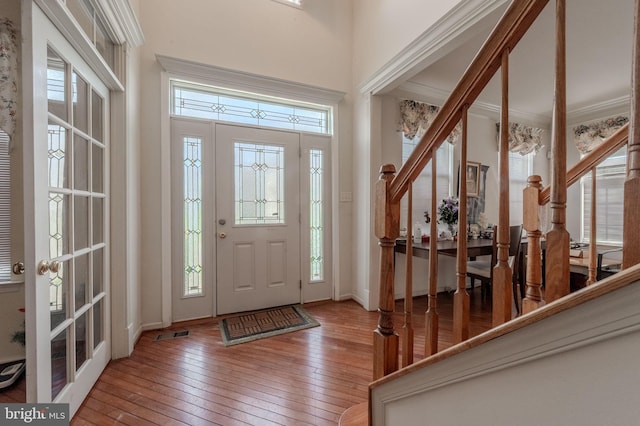 entryway with a high ceiling, stairs, hardwood / wood-style floors, and visible vents