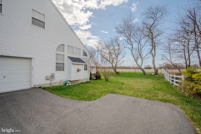 view of yard with an attached garage and fence