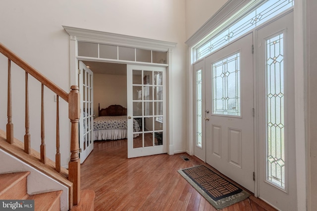 foyer entrance with visible vents, wood finished floors, and stairway