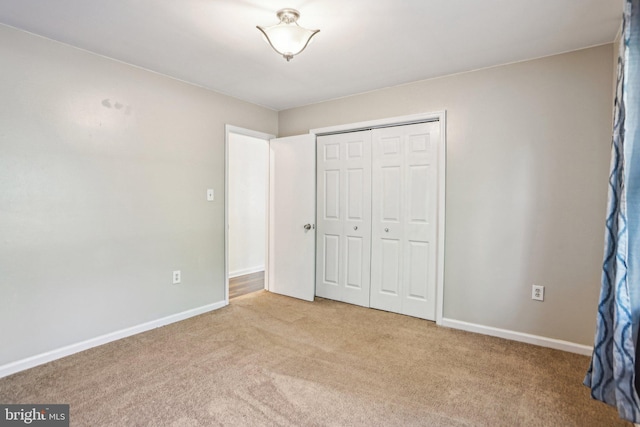 unfurnished bedroom with baseboards, carpet flooring, and a closet