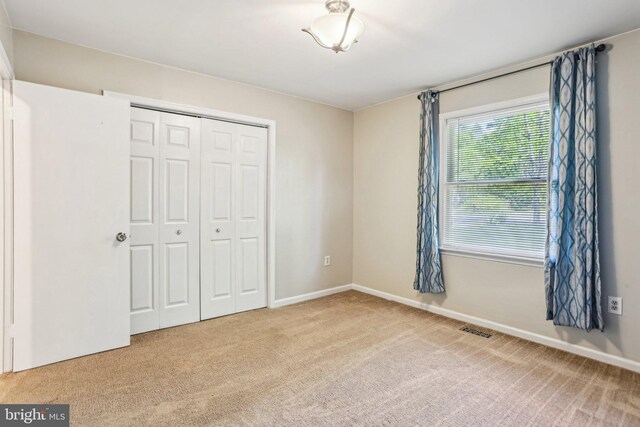 unfurnished bedroom featuring a closet, visible vents, carpet flooring, and baseboards