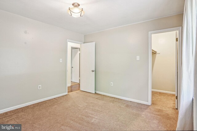 unfurnished bedroom with baseboards, carpet flooring, and a spacious closet