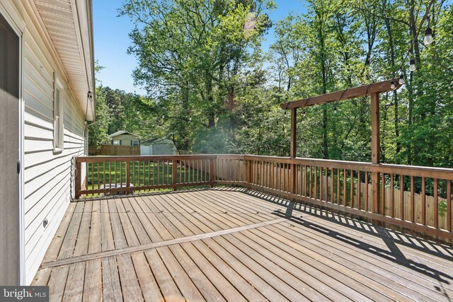 wooden terrace featuring a fenced backyard, an outbuilding, and a storage shed