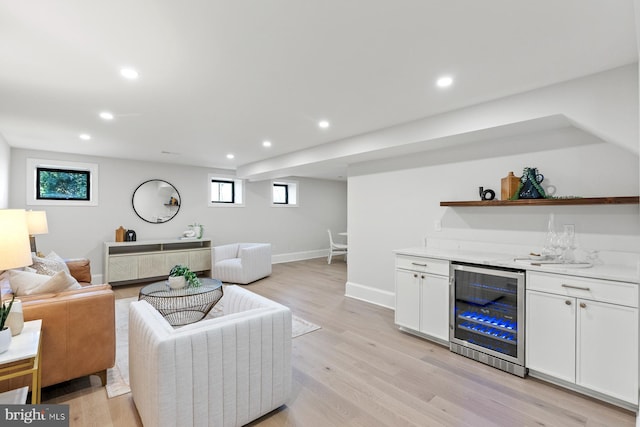 living room with recessed lighting, light wood finished floors, beverage cooler, and a bar