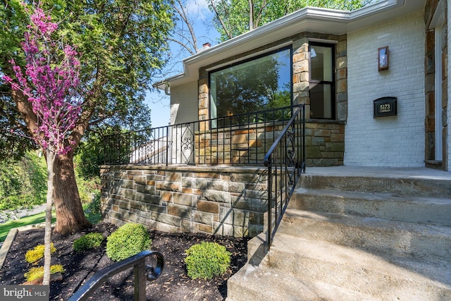 view of exterior entry featuring brick siding and stone siding