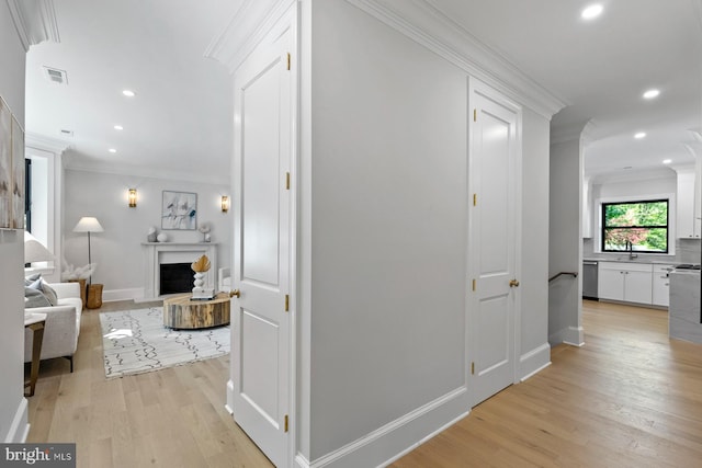 corridor featuring light wood-type flooring, baseboards, recessed lighting, and ornamental molding