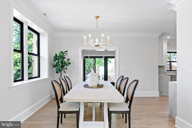 dining room with light wood-style flooring, crown molding, baseboards, and an inviting chandelier