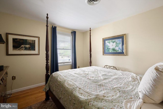 bedroom featuring baseboards, visible vents, and wood finished floors
