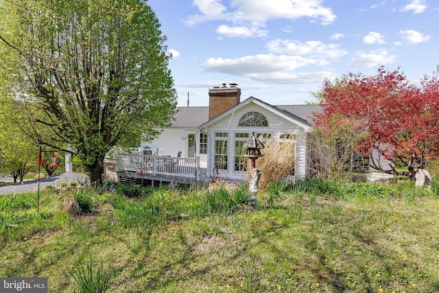 back of property with a chimney and a deck