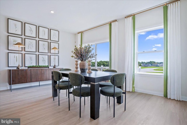 dining space featuring baseboards and light wood-style floors