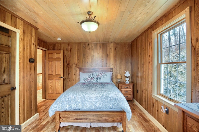bedroom with light wood-style floors, wooden ceiling, and wood walls