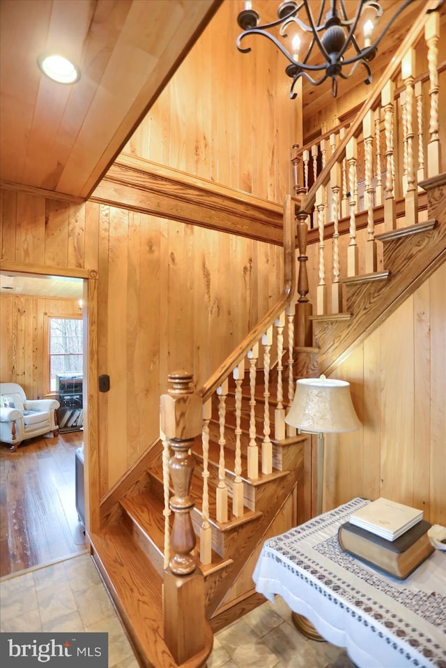 stairs featuring wood walls and a chandelier