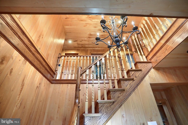 stairs with a chandelier and wood walls