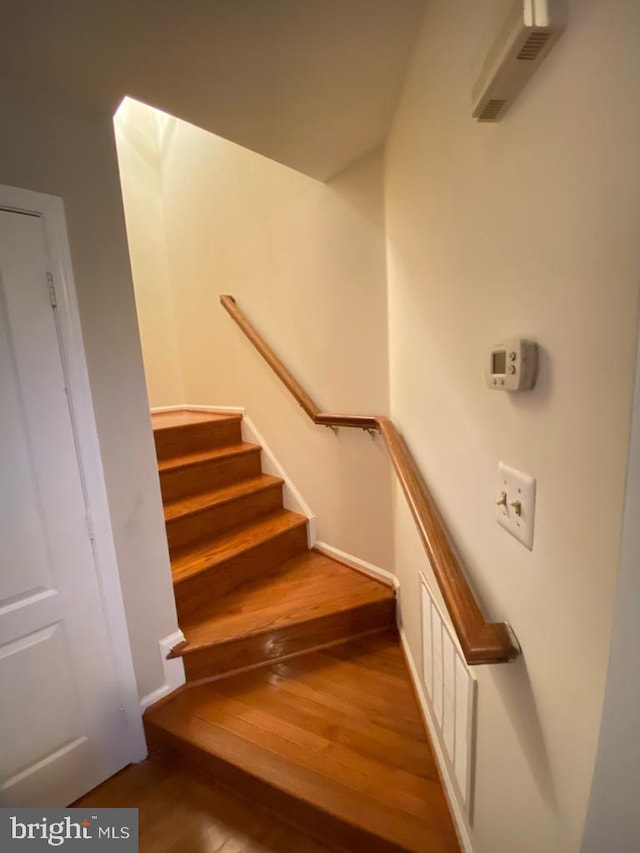 stairway with wood finished floors and baseboards
