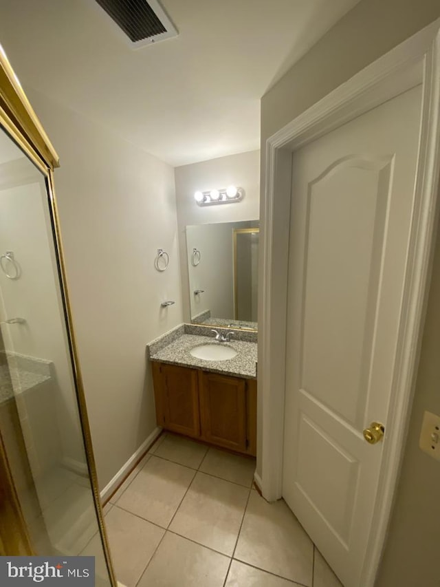 bathroom featuring tile patterned floors, vanity, baseboards, and a shower with shower door