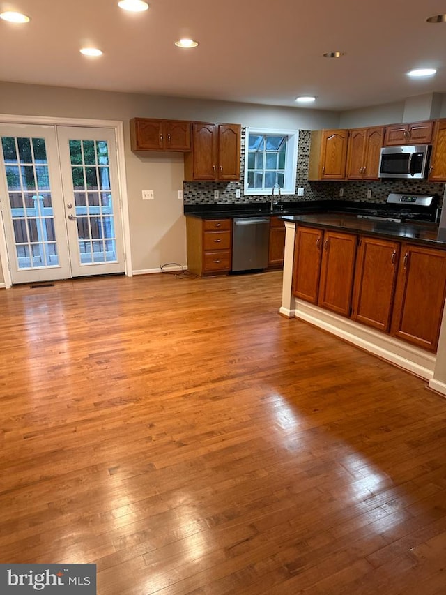 kitchen featuring stainless steel appliances, dark countertops, light wood-style flooring, a sink, and recessed lighting
