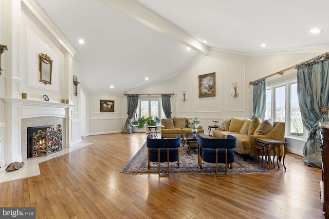 living area with a fireplace with flush hearth, hardwood / wood-style floors, a decorative wall, and lofted ceiling with beams