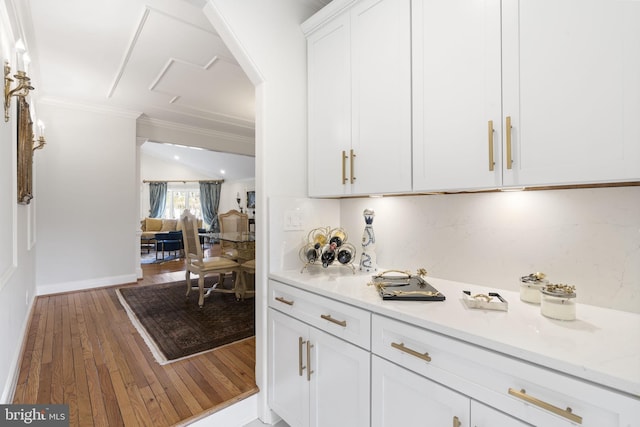 bar with hardwood / wood-style floors, baseboards, ornamental molding, and arched walkways