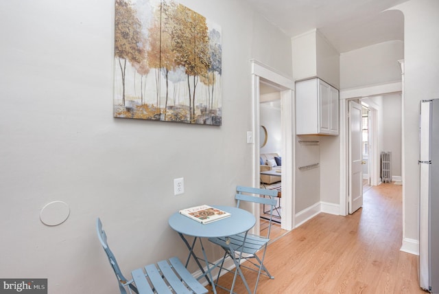 dining room featuring light wood finished floors, radiator heating unit, and baseboards