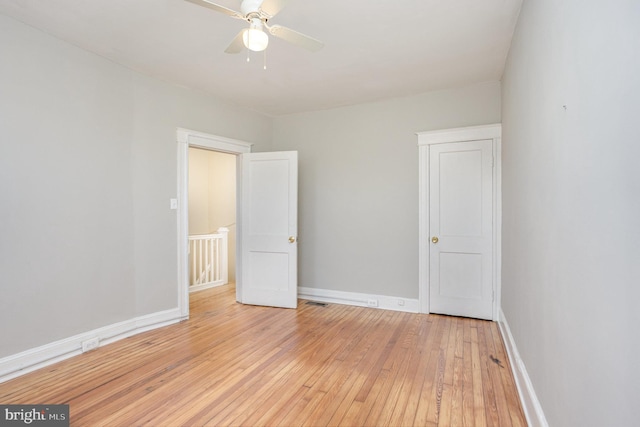 spare room featuring light wood-style floors, baseboards, and ceiling fan